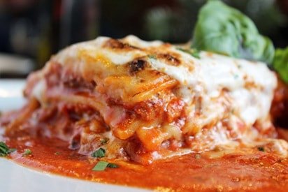 A slice of lasagna topped with melted cheese and red sauce
